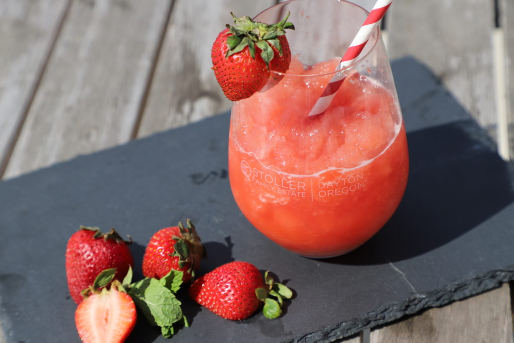 Stoller Family Estate Frosé on a black slab with cut strawberries
